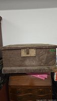 Front view of the vintage wooden tool chest showing metal latch and handles, aged wood surface with wear.