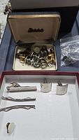 Mixed vintage men's jewelry including cuff links, cuff buttons, and tie tacks inside a Birkdale branded box and loose pieces.