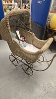 Side view of full vintage wicker pram with hood, plush toys inside, and metal wheels.