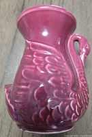 Photo of burgundy red swan-shaped ceramic vase showing wing texture and swan neck handle details.