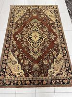 Full view of rectangular hand-knotted Persian rug with brown background and floral medallion design.