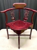 Front view of the antique Asian rosewood corner chair showing the floral carved backrest, curved seat, and lacquer finish.