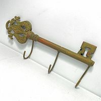 View of full skeleton key shaped cast iron wall hanger showing ornate handle and three hooks.