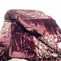 Close-up view of the folded duvet showing the deep burgundy plush velvet texture combined with the patterned silk fabric featuring beige floral and dot art deco motifs.