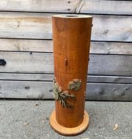 Full height image of the wooden wallpaper roller with decorative metal leaves on wooden background