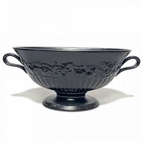 Front view of the black Carlton ware urn showing footed base, two handles, and embossed floral design on body.
