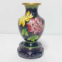 Front view of cloisonné vase showing colorful floral enamel design and brass rim on hand carved wooden stand.