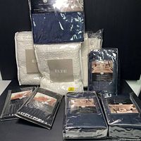 Full lot view showing packaged white euro pillow shams, black king pillow cases, and navy bedding sets.