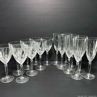 16 Italian crystal glasses displayed in two rows, showing both champagne flutes and wine glasses with cut crystal patterns.