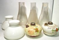 Seven pieces of oil lamps including four frosted glass chimneys and three painted glass lamp reservoirs with metal fittings.