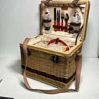 Wicker picnic basket showing interior with cutlery, glasses, salt and pepper shakers
