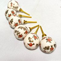 Final overview of all six porcelain hand painted drawer pulls arranged in a line with visible gold screws.