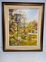 Full view of the framed oil on canvas painting showing the scene of a birdhouse on a post, trees, fence, and a small building in the background.