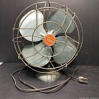 Front view of vintage Torcan electric table fan with metal blades and cage, showing electric cord and plug.