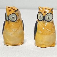 Front view of pair of yellow lustreware owl salt and pepper shakers showing large painted eyes and multiple holes on top.