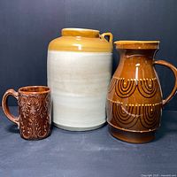 Front view of the three stoneware items arranged side by side showing size and design differences.