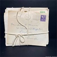 Front view of approximately 20 vintage WWII era envelopes tied with string showing handwritten addresses and stamps.