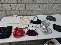 10 vintage purses on white table, showing variety of colors and styles