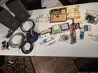 Overview photo showing speakers, wires, boxed parts, bulbs, switches, and packaged components on a white table.