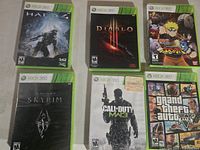 Front view of six Xbox 360 game cases showing cover art for Halo 4, Diablo III, Naruto Shippuden Ultimate Ninja Storm 3, Skyrim, Call of Duty MW3, GTA V.