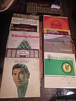 Top view of open black carrying case showing approximately 30 vintage 33⅓ RPM vinyl records with various album covers visible including Christmas and folk music titles.