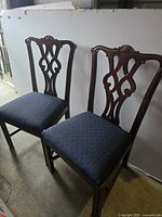 Pair of vintage Chippendale style side dining chairs with dark wooden frames and blue upholstered seats, showing front view of seat and backrest details.