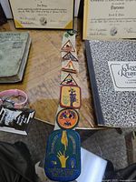 Top view of Girl Scout badges on table along with diplomas, class reunion book, telephone directory and handbook.
