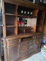 Full view of two-section wooden bar hutch showing multiple shelves including row for stemware, drawers and cabinet doors below