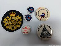 Front view of assorted Toronto Police and OPP buttons and badge showing designs and logos.