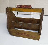 Front view of vintage wooden Coca-Cola bottle caddy showing original paint and red logo.