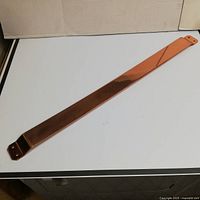 Full length view of solid copper door push bar on white surface showing overall condition and shape.