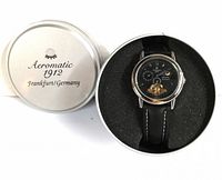 Watch mounted in branded round metal storage tin with removable lid