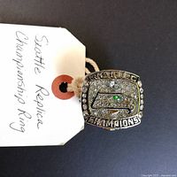 Front view of Seattle Seahawks replica championship ring showing logo and 'WORLD CHAMPIONS' text with rhinestones.