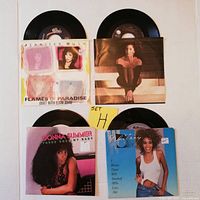Four 45 RPM records in original picture sleeves, including Jennifer Rush, Donna Summer, Cher, and Whitney Houston with a Set H note.