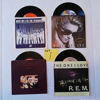 Top-down photo of all four 45 RPM vinyl records with original picture sleeves laid out on a white background. Shows front of each sleeve.