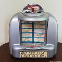 Front view of silver metal housing with clear window, song title strips and push-button selectors.