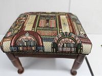 Full view of footstool showing tapestry upholstery with jukebox and cassette tape design and wooden legs.