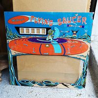 Front view of the Flying Saucer Midway arcade back glass showing the colorful saucer, alien figure, and scenic background with space elements.