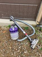 Dyson DC37 vacuum with hose, wand and floor head on gravel surface