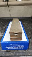 Front view of steel hinged safety deposit box on cardboard box
