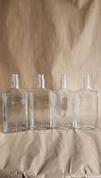 Front view of four clear glass liquor bottles showing shape and clarity