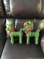 Two artificial greenery reindeer on leather sofa