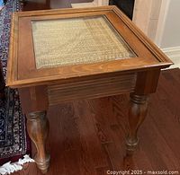Side angle view showing the table's turned legs and framed glass and rattan inset top