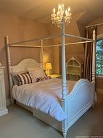 Angled view of assembled white four poster bed frame in a bedroom setting
