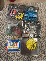 Photo showing metal cooling rack, packaged marine animal cookie cutters, plastic bag with red and green plastic cookie cutters, metal baking pan holding loose metal cookie cutters, and two cookie cutter sets in tins.
