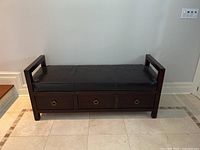 Front view of the Bernhardt solid wood bench with black leather cushion and three drawers closed.