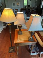 One floor lamp and two table lamps arranged on hardwood floor and wooden coffee table