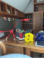 Photo of desk surface with red adjustable desk lamp, multi-container supply holder with colored pencils and scissors, and large yellow and blue letter bookends shaped as 'a' and 'z'.