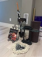 Overall photo showing heart shaped mirror with decorative floral border, metal book display easel with book, black bankers lamp, leather containers, and umbrella holder with umbrella.