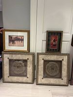 Four framed art pieces: gold frame print, wine bottle print, and two framed Chinese coin metal artworks